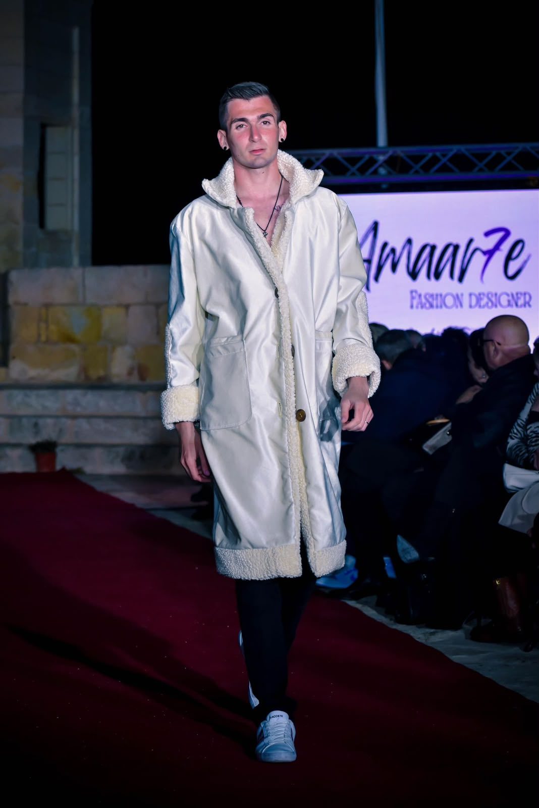 Abrigo marfil en pasarela frente al logotipo Amaar7e Fashion Designer